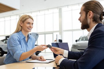 Rich woman customer client signing contract with salesman in car showroom