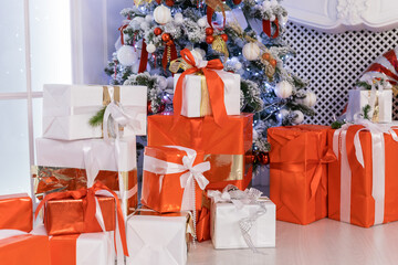 colorful Gift boxes with a large red bow against christmas tree. Luxury New Year gift. Christmas presents. Christmastime celebration
