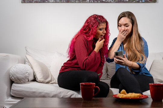 Par de amigas mujeres viendo el celular con sorpresa, por la llegada de una noticia
