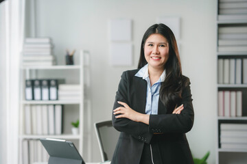 Businesswoman is smiling while standing in her office with her arms crossed looking confident