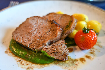 Roasted meat and vegetables served on a plate in a restaurant.