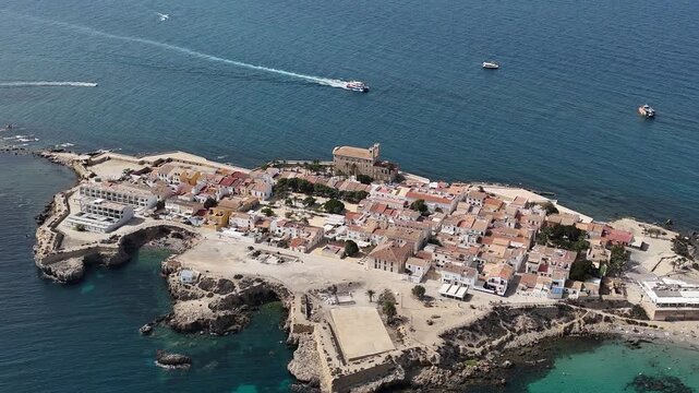 Tabarca, Spain from the air. Bright sunny day, azure water, yachts anchored in the bay. Tranquil sea, vibrant city, and beach crowded with tourists. Costa Brava attraction.