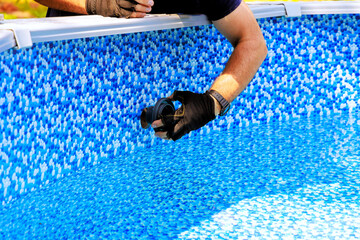 Chlorination water filtration system installed in swimming pool frame by worker