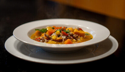 Close-up view of a traditional Chilean carbonada plate, showcasing hearty meat, potatoes, corn, and vegetables in a rich broth.