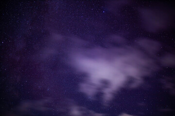 night starry sky outside the city with purple reflections of the northern lights