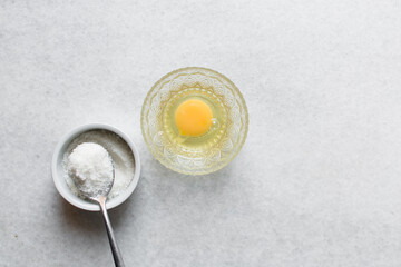 Overhead view of egg and sugar on a marble countertop, process of making meringue