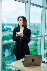 Fototapeta premium Young business woman talking on the phone while working in a modern office. Businesswoman customer sales manager of the company in a suit, at the workplace.