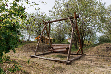 Wooden swing for rest in summer camp on background of camping tent for outdoor holiday and vacation