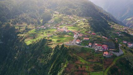 Terraced mountains village sunlight drone view. Rural community on green fields