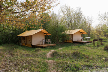 Obraz premium Cozy open glamping tents with light inside in summer camp. Camping tent for holiday and vacation
