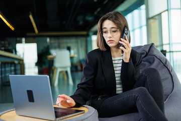 Young smiling professional businesswoman, happy confident female sales manager standing in modern office working online. A modern woman works on a laptop