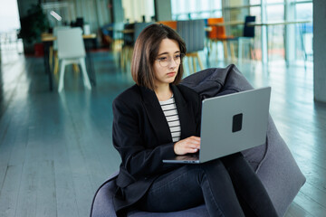 Smiling business woman, company employee, working holding laptop while sitting in modern office....