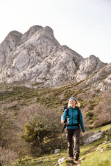 Fototapeta premium Smiling hiker walking with mountain in the background