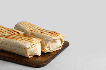 Board with tasty shawarma on grey background
