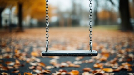 An isolated swing hangs silently amidst fallen autumn leaves in a serene park, evoking the emotions tied to loneliness, nostalgia, and the quiet beauty of a deserted playground.