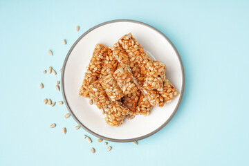Plate with tasty kozinaki and sunflower seeds on blue background
