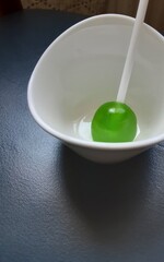 Green lollipop in a small white bowl close up..