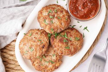 Cutlets with chopped parsley, ketchup and forks on white grunge table in kitchen