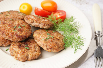 Plate with cutlets, dill and tomatoes on white grunge table in kitchen