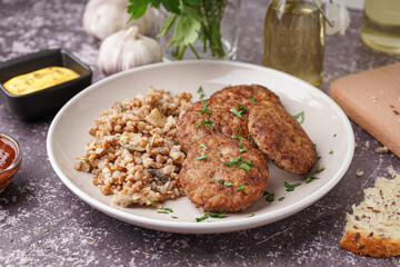 Cutlets with buckwheat, mushrooms and parsley on grey grunge table in kitchen