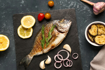 Slate board with tasty grilled dorado fish on grey background