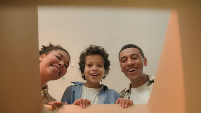 POV point of view inside cardboard box African American family parents little boy kid child open unpack parcel online shopping delivery happy excited mother father son unboxing unpacking moving day
