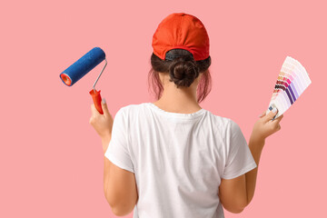 Young woman with paint roller and palette samples on pink background
