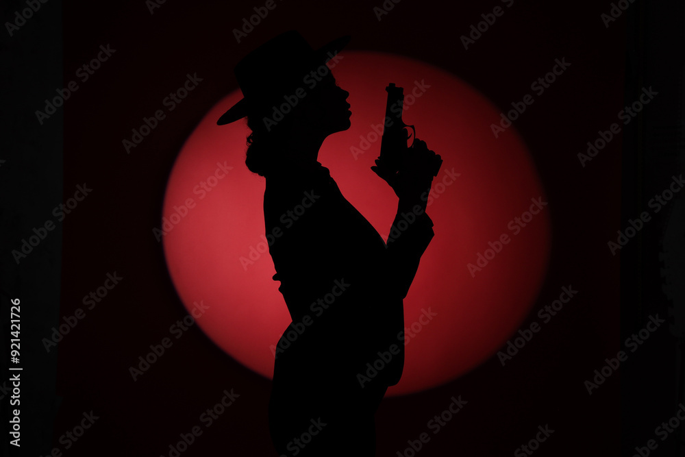 Wall mural silhouette of female spy with gun on dark background