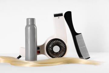 Hair spray with strand, comb and blow dryer on white background