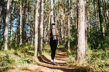 Obraz premium Young caucasian woman walking through forest with yoga mat 