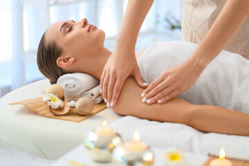 Physiotherapist giving massage to young woman in spa salon