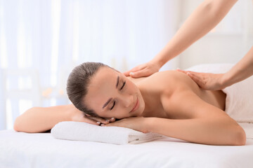 Obraz premium Relaxed young woman getting massage by therapist in spa salon