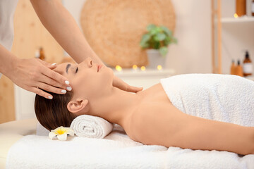 Beautiful young woman receiving facial massage in spa salon