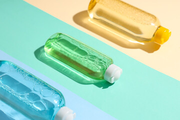 Bottles of micellar water on color background, closeup