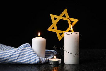 Prisoner uniform, burning candles and Star of David on dark background. Holocaust Remembrance Day