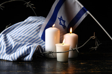 Prisoner uniform, burning candles, barbed wire and flag of Israel on dark background. Holocaust...