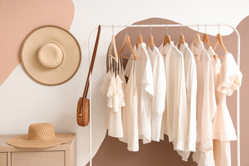 Rack with white clothes near color wall in room