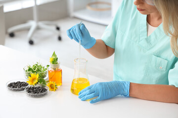 Female scientist with flasks of samples, sunflower seeds and sprouts working in laboratory, closeup