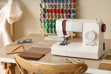 Sewing machine with fabric samples on tailor's table in atelier