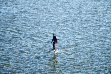 Man on an eFoil board gliding over calm blue water