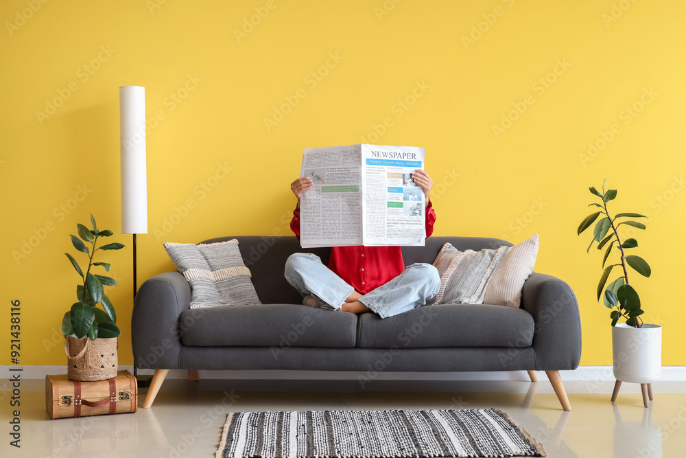 Poster Woman with newspaper sitting on sofa at home