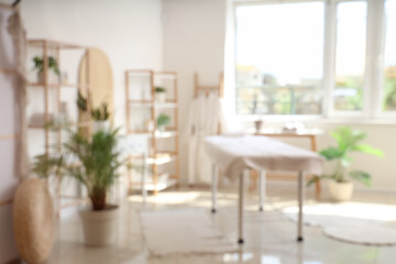 Blurred view of light spa salon with couch, shelving units and folding screen