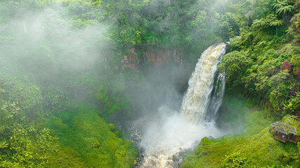 Telun Berasap Falls in green forest. Waterfall in the tropical mountain jungle. Sumatra, Jambi, Indonesia.