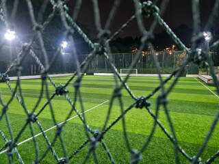 Soccer field or pitch with artificial grass behind the mesh in the sports complex arena in the...