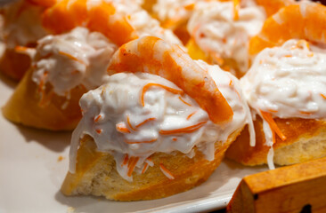 Typical snacks of Basque Country, pinchos or pinxtos skewers with small pieces of bread, fish, sea food, sweet green pepper served in bar in San-Sebastian or Bilbao, Spain