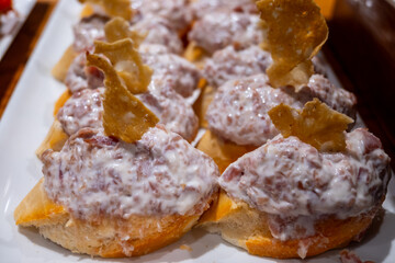 Typical snacks of Basque Country, pinchos or pinxtos skewers with small pieces of bread, fish, sea food, sweet green pepper served in bar in San-Sebastian or Bilbao, Spain