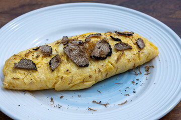 French omelette with mushrooms, fresh farmers eggs and black summer truffle mushroom in pieces for making truffle dishes with tasty aroma