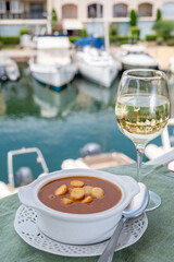 Homemade tasty fish or bisque soup with croutons served with glass of cold white wine and view on...