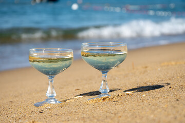 Summer time on French Riviera, two coupe glasses of champagne cremant sparkling wine on Pampelonne sandy beach near Saint-Tropez in sunny day, Var, vacation in France