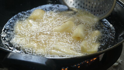 Cassava is being fried on a frying pan. Fried cassava is a traditional Indonesian food. Focus selected